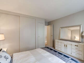 This bedroom features a spacious closet and a classic white dresser with a large mirror, perfect for organizing your belongings.