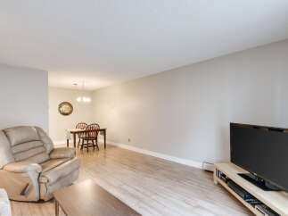 This spacious living and dining area features a comfortable recliner, a dining table with chairs, and a modern television setup.