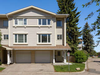 Discover this charming townhouse featuring a neutral-toned exterior with beige siding and a brown roof.