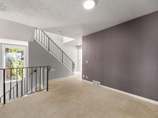 This spacious hallway features a neutral-toned carpet and a prominent dark gray accent wall, perfect for showcasing artwork.