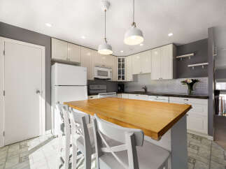 This spacious kitchen features a large wooden island with seating, perfect for casual dining and entertaining.