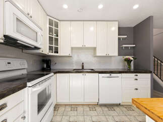 This bright and airy kitchen features crisp white cabinetry, a subway tile backsplash, and a sleek microwave oven.