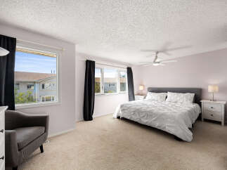 Step into this inviting bedroom, featuring a plush king-sized bed with crisp white linens and a stylish grey headboard.