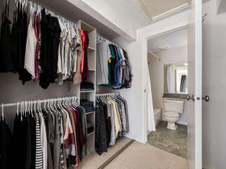 Discover ample storage in this spacious walk-in closet, featuring multiple hanging rods and shelving units.