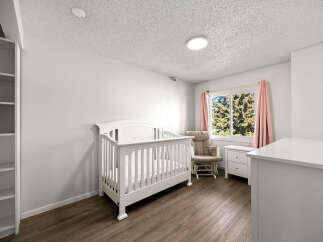 Welcome to this charming nursery, featuring a classic white crib and a comfortable glider chair perfect for soothing your little one.