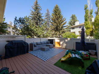 Enjoy outdoor living on this spacious deck featuring a comfortable sectional sofa, coffee table, and a stylish striped rug.