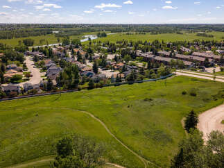 Discover this charming suburban neighborhood with a mix of single-family homes and townhouses, nestled beside a lush green park and a serene river.