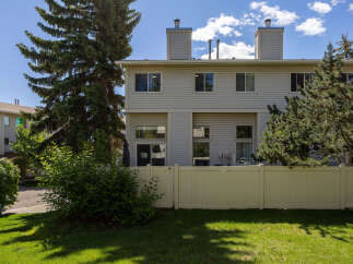 Enjoy private outdoor living in this charming townhouse backyard, complete with a white vinyl fence and lush green lawn.