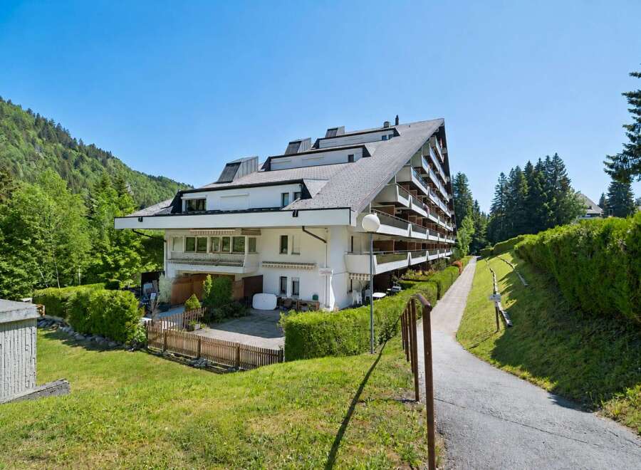 Discover this stunning multi-story apartment building nestled amidst lush greenery and rolling hills.