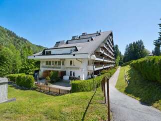 Discover this stunning multi-story apartment building nestled amidst lush greenery and rolling hills.