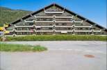 Discover this unique triangular apartment building nestled against a lush green hillside, offering stunning mountain views.