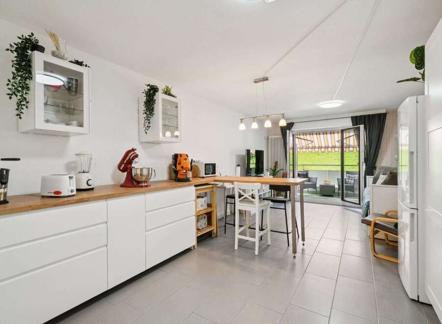 Discover this modern kitchen featuring sleek white cabinetry and a warm wooden countertop, perfect for meal preparation.