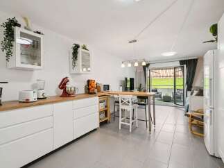 Discover this modern kitchen featuring sleek white cabinetry and a warm wooden countertop, perfect for meal preparation.