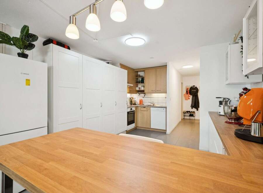Discover this modern kitchen featuring ample white cabinetry and a sleek Bosch refrigerator.