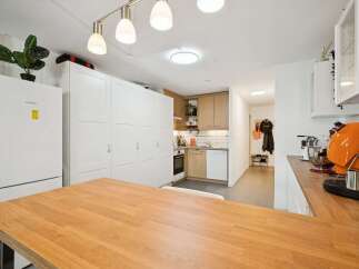 Discover this modern kitchen featuring ample white cabinetry and a sleek Bosch refrigerator.