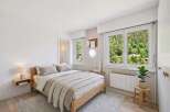 Experience serene living in this charming bedroom, featuring a comfortable bed adorned with plush linens and a cozy knit throw.