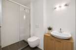 This modern bathroom features a sleek glass-enclosed shower and a wall-mounted toilet for a minimalist aesthetic.