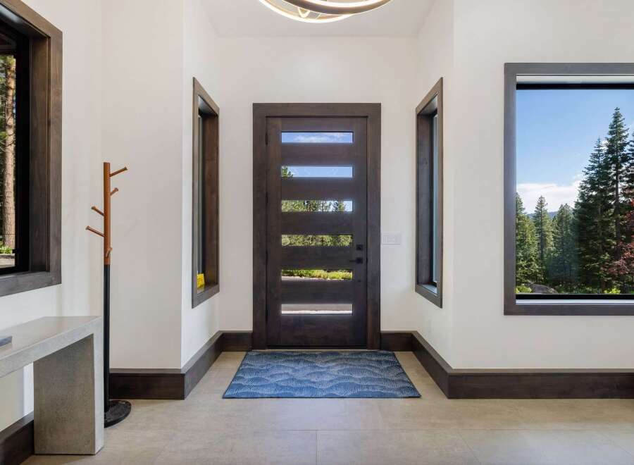 Step into this inviting entryway featuring a modern dark wood door with horizontal glass panels, allowing natural light to flood the space.