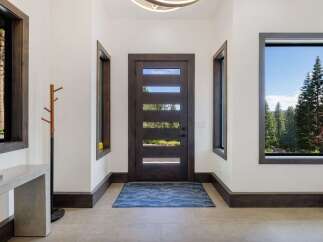 Step into this inviting entryway featuring a modern dark wood door with horizontal glass panels, allowing natural light to flood the space.