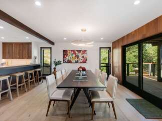 Experience modern living in this stunning dining area, featuring a sleek dark wood table surrounded by elegant cream upholstered chairs.
