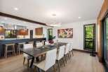 Experience modern living in this stunning dining area, featuring a spacious dark wood table complemented by elegant white chairs.