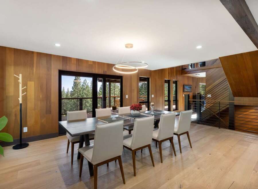 Experience luxurious mountain living in this stunning dining room, featuring warm wood paneling and expansive windows that frame breathtaking forest views.