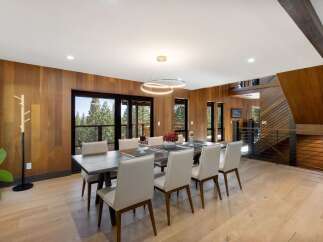 Experience luxurious mountain living in this stunning dining room, featuring warm wood paneling and expansive windows that frame breathtaking forest views.