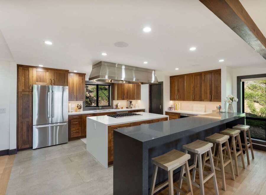 Experience luxury and functionality in this stunning modern kitchen, featuring rich walnut cabinetry and a sleek stainless steel range hood.