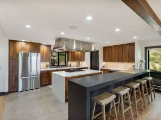 Experience luxury and functionality in this stunning modern kitchen, featuring rich walnut cabinetry and a sleek stainless steel range hood.