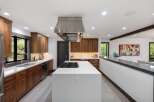 Experience luxury in this modern kitchen featuring sleek walnut cabinetry and a spacious quartz island with a built-in gas range.