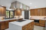 Experience luxury in this modern kitchen featuring rich walnut cabinetry and a sleek stainless steel range hood.