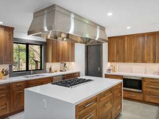 Experience luxury in this modern kitchen featuring rich walnut cabinetry and a sleek stainless steel range hood.