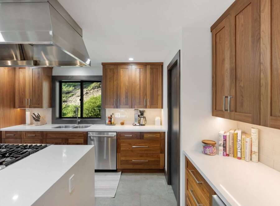 Experience modern luxury in this stunning kitchen featuring sleek walnut cabinetry and pristine white countertops.