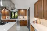 Experience modern luxury in this stunning kitchen featuring sleek walnut cabinetry and pristine white countertops.