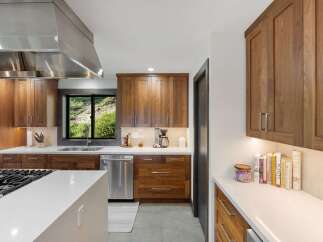 Experience modern luxury in this stunning kitchen featuring sleek walnut cabinetry and pristine white countertops.