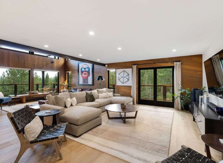 Experience luxurious living in this stunning modern home, featuring a spacious open-concept living area with floor-to-ceiling wood paneling and expansive windows that offer breathtaking forest views.