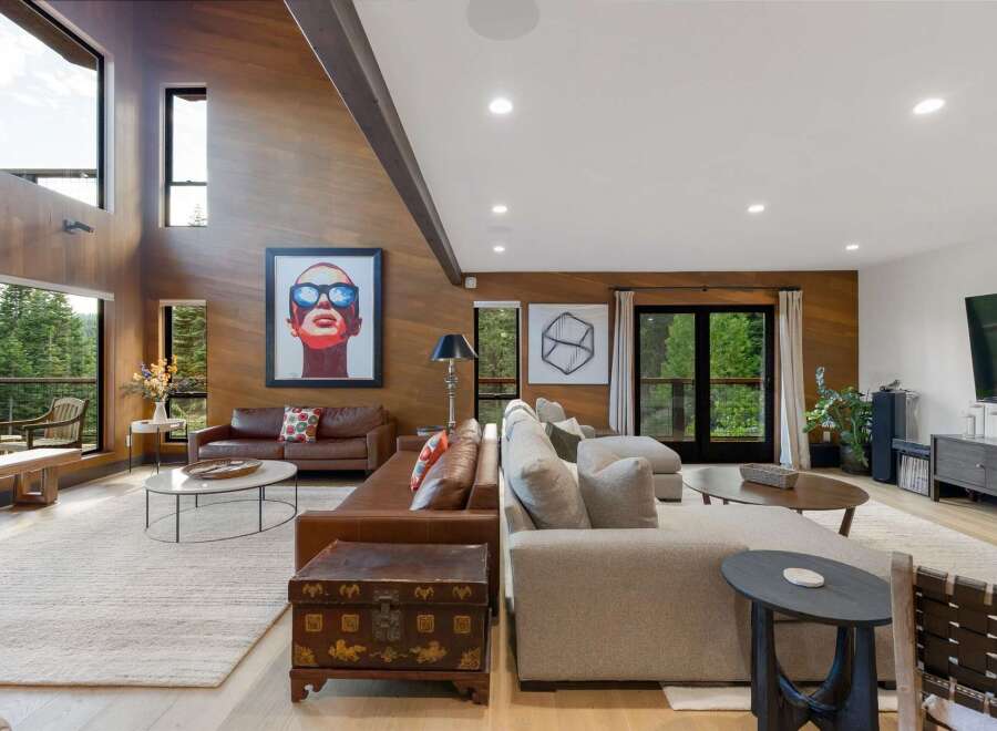 Experience luxurious living in this stunning modern home, featuring a spacious open-concept living area with soaring wood-paneled ceilings and a dramatic vaulted beam.