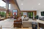 Experience luxurious living in this stunning modern home, featuring a spacious open-concept living area with soaring wood-paneled ceilings and a dramatic vaulted beam.