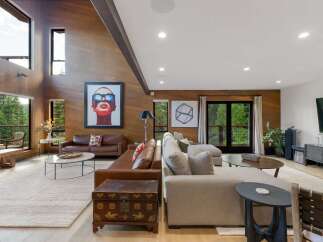 Experience luxurious living in this stunning modern home, featuring a spacious open-concept living area with soaring wood-paneled ceilings and a dramatic vaulted beam.
