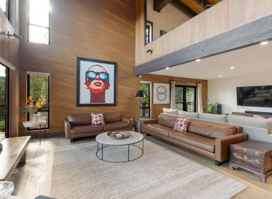 Experience luxury living in this stunning modern home featuring a soaring wood-paneled living room with a dramatic vaulted ceiling and abundant natural light.