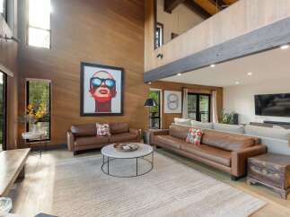 Experience luxury living in this stunning modern home featuring a soaring wood-paneled living room with a dramatic vaulted ceiling and abundant natural light.