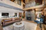 Experience luxury living in this stunning great room, featuring a dramatic floor-to-ceiling stone fireplace and a soaring vaulted ceiling with exposed beams.