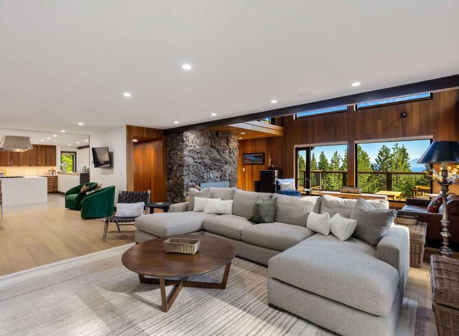 Experience breathtaking mountain and lake views from this stunning living room, featuring a large sectional sofa perfect for relaxation.