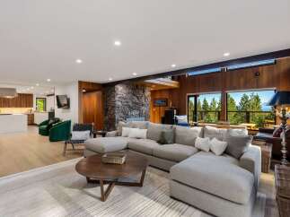 Experience breathtaking mountain and lake views from this stunning living room, featuring a large sectional sofa perfect for relaxation.