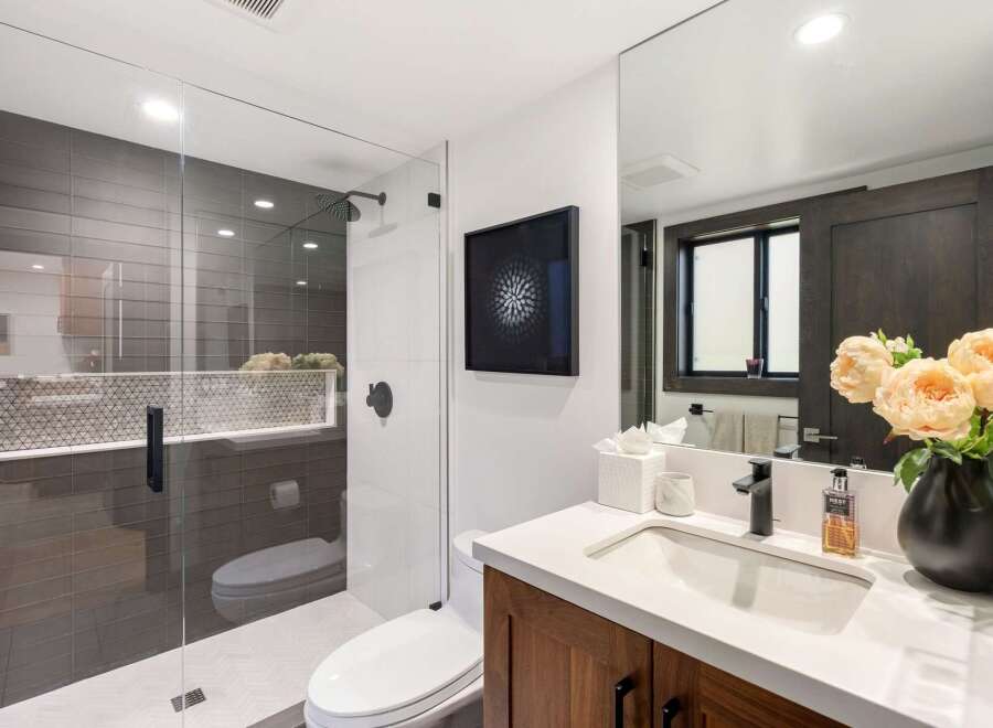 Experience modern luxury in this stunning bathroom, featuring a sleek glass-enclosed shower with sophisticated gray tilework and a chic geometric accent.