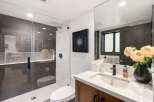 Experience modern luxury in this stunning bathroom, featuring a sleek glass-enclosed shower with sophisticated gray tilework and a chic geometric accent.