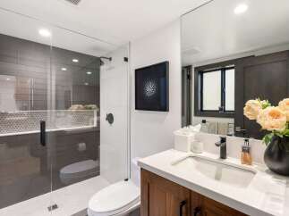 Experience modern luxury in this stunning bathroom, featuring a sleek glass-enclosed shower with sophisticated gray tilework and a chic geometric accent.