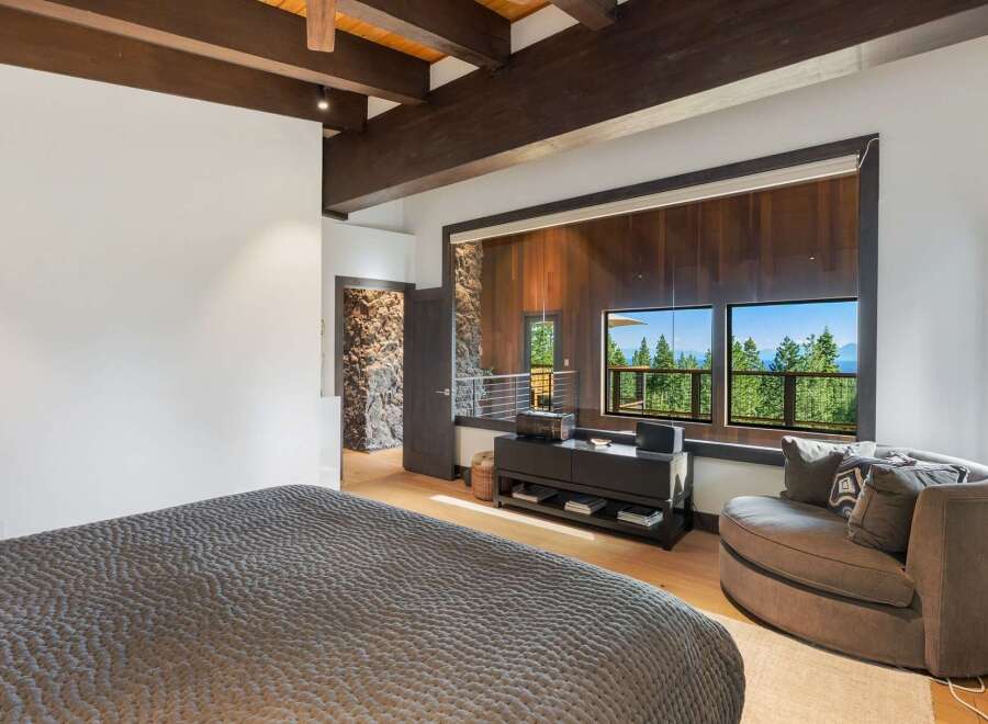 Experience breathtaking mountain views from this luxurious bedroom, featuring a cozy seating area and expansive windows.
