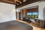 Experience breathtaking mountain views from this luxurious bedroom, featuring a cozy seating area and expansive windows.