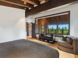 Experience breathtaking mountain views from this luxurious bedroom, featuring a cozy seating area and expansive windows.